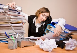 Young tired businesswoman with tons of documents calling phone